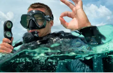 Scuba diver in Playa del Carmen giving an OK signal, holding a pressure gauge during a PADI course."